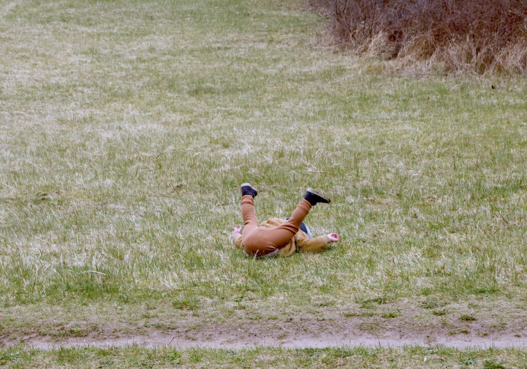 pret maken in het bos als tegenovergestelde effect van schermtijd. Peuter rollebolt in het gras.